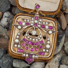 This beautiful pendant is accented with one (1), bezel set, round brilliant cut diamond, five (5), bead set, round brilliant cut diamonds, twenty-seven (27), bead set, oval/round mixed cut natural rubies and twenty-four (24), bead set, seed pearls. The pendant measures 52.1mm X 38.4mm. The pendant is suspended from a 14K yellow gold 18 inch long neck chain finished with a gold-filled spring ring clasp. Oval Pink Jewelry With Single Cut Diamonds, Pink Oval Jewelry With Single Cut Diamonds, Fine Jewelry With Rose Cut Diamonds In Oval Pendant, Fine Jewelry With Rose Cut Diamonds Oval Pendant, Fine Jewelry With Oval Jeweled Details, Fine Jewelry With Jeweled Oval Details, Oval Jeweled Fine Jewelry, Elegant Multi-stone Oval Pendant Jewelry, Fine Jeweled Round Jewelry