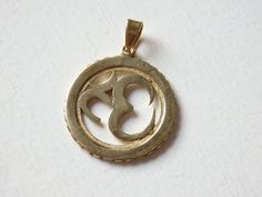 "A beautiful, brass Om pendant from Nepal. It comes with bail already attached, ready for threading on to leather, cord or chain. These lovely gold-tone Nepalese brass pendants measure 26mm (1\") in diameter. The bail has an inside diameter of approximately 4mm. The last picture shows the reverse side of the pendant. This listing is for ONE pendant. Other Nepali 'Om' pendants available in other styles! Check out the Pendants section and the 925 Sterling silver section to see all available pendan Gold Brass Pendant Jewelry, Symbolic Gold Jewelry With Large Pendant, Gold Pendant Jewelry Cadmium-free, Gold Brass Round Pendant Jewelry, Gold Oval Pendant Jewelry, Gold Brass Jewelry With Large Pendant, Cadmium-free Gold Pendant Jewelry, Symbolic Brass Jewelry With Round Pendant, Gold Brass Oval Pendant Jewelry