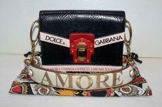 Dolce & Gabbana Leather and Ayers Skin Embroidered Lucia Shoulder Bag Black The Lucia bag is a key accessory in the wardrobe of every Dolce & Gabbana woman. It’s perfect for every occasion and is the epitome of the handcrafted tradition and attention to detail that characterizes the brand. Shoulder bag from the Lucia line in iguana print ayers snakeskin and calfskin with detail in printed calfskin and embroidered strap • Closure in light galvanized gold wrapped in calfskin with rounded studs • D Designer Shoulder Bag For Gift, Designer Shoulder Bag With Adjustable Strap As Gift, Goldwork Embroidery, Expensive Bag, Smartphone Holder, Gold Wrap, Key Accessories, Overnight Bags, Gold Work