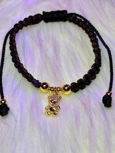 a black and gold beaded bracelet with an initial charm hanging from it's center