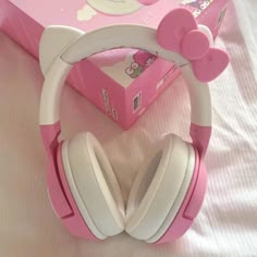 hello kitty headphones sitting on top of a bed next to a pink box with white ears