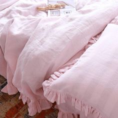 a bed with pink sheets and pillows on top of it