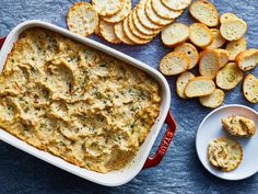 a casserole dish with bread and crackers next to it on a blue surface