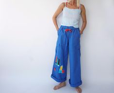 Ultra-flattering high waist cargo pants with drawstring waist from the 90s era. Slightly flared with foldover waistband. Graphic details on front & back that make them special. Very comfortable. In excellent condition. Measurements are taken flat. Fit actual M Waist = 13.5" in (un-stretched) / 34 cm (un-stretched) Hip = 19.5 in / 50 cm Rise = 12.5 in / 32 cm Inseam = 29 in / 73 cm Total length = 40 in / 102 cm Model is 5'6", 26" waist, 36" hip and wears a modern 2-4 Fit guide: It's always a good 90s Style High Waist Blue Pants, 90s High Waist Blue Pants, 90s Style Blue Bottoms With Cargo Pockets, 90s Style Blue Cargo Bottoms, 90s Blue Cargo Bottoms, 90s Blue Bottoms With Cargo Pockets, Retro Spring Pants With Cargo Pockets, Retro Pants With Cargo Pockets For Spring, Retro Cargo Pants For Spring