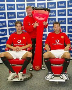 three men in red shirts are posing with a giant frisbee