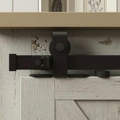 a close up of a sliding door handle on a wooden cabinet with white painted walls in the background