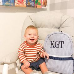 a young boy sitting in a chair next to a backpack