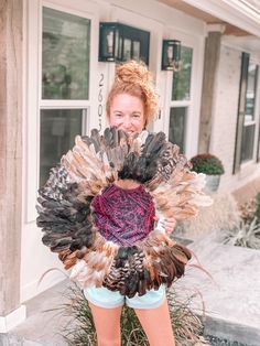 a woman holding a large turkey in front of her face and smiling at the camera