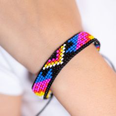 Get ready to make a statement with the Bold Bracelet! This vibrant, handwoven accessory features eye-catching, indigenous patterns in a riot of bright colors. It’s designed to stand out and add a pop of fun to any outfit. With an adjustable sliding knot on the back, it ensures the perfect fit for any wrist. Whether you’re dressing up for a festival or just want to spice up your everyday look, the Bold Bracelet is here to bring a splash of joy and culture to your style. Slip it on and let your bo Casual Rainbow Friendship Bracelets With Sliding Knot, Casual Rainbow Beaded Bracelets With Sliding Knot, Adjustable Rainbow Friendship Bracelets With Colorful Beads, Bohemian Rainbow Bracelets With Adjustable Cord, Adjustable Rainbow Friendship Bracelet With Colorful Beads, Hippie Multicolor Adjustable Friendship Bracelets, Rainbow Festival Jewelry With Adjustable Cord, Rainbow Jewelry With Adjustable Cord For Festivals, Rainbow Adjustable Cord Jewelry For Festivals