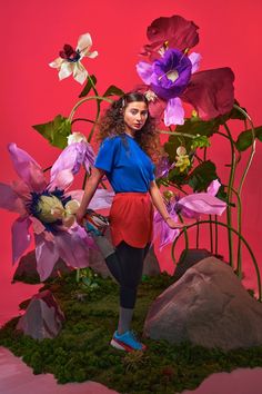 a young woman standing in front of flowers