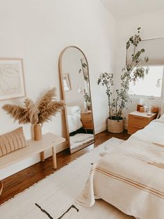 a bedroom with a bed, mirror and plants