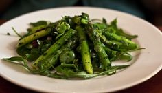 a white plate topped with asparagus on top of a wooden table