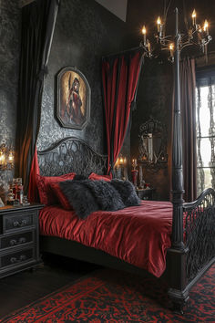 a bed with red sheets and pillows in a dark room next to a large window