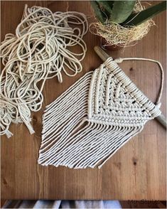 two pieces of woven material sitting on top of a wooden table next to a potted plant