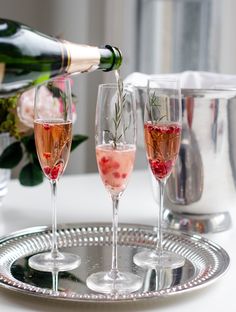 champagne being poured into wine glasses on a silver platter with flowers in the background