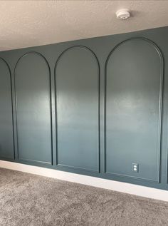 an empty room with blue walls and gray carpet