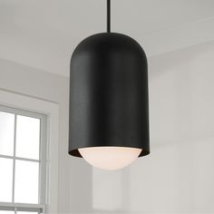 a black lamp hanging from the ceiling in a room with white walls and window behind it