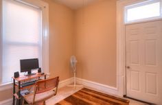 a room with a desk, chair and computer on the floor next to a door