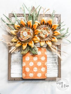 some flowers are sitting on top of an orange and white polka dot napkins in a wooden frame