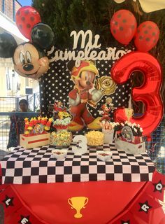 a mickey mouse themed birthday party with balloons and food on the table for guests to eat