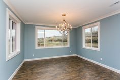 an empty room with blue walls and wood flooring, chandelier hanging from the ceiling