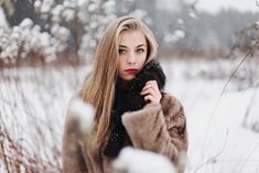 a woman with long blonde hair wearing a fur coat and posing for the camera in snow