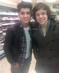 two young men standing next to each other in front of a grocery store display case