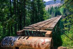 an old train track in the woods with graffiti on it