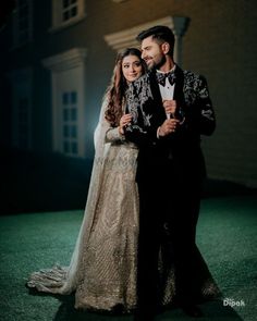 a man and woman standing next to each other in front of a building at night