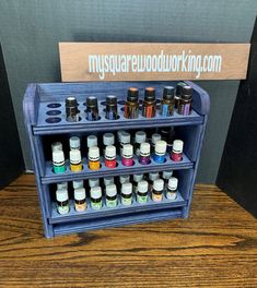 a display case with many bottles of essential oils on it and a sign behind it that says mysuravewoodworking com