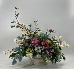 a vase filled with lots of flowers and greenery