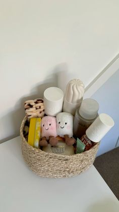 a basket filled with lots of different items on top of a white table next to a wall