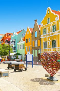 colorful buildings line the waterfront in front of a body of water with benches on each side