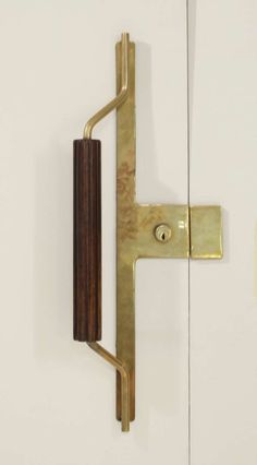 a door handle on the side of a white wall next to a brown wooden pole