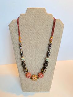 Stunning Handmade Dayak (Borneo) Beads Necklace. Hand painted beads with different color tone.  The unique and meticulous patterns inscribe on each bead. Hailing all the way from the island of Kalimantan in Indonesia, these beads are carefully handcrafted using the finest materials including carnelian, crystal, clay and other natural stone.  In the same way each stroke of red, yellow and blue paint depicts the unequivocal talents of the craftsman. Bohemian Czech Glass Beads With Large Beads, Bohemian Czech Glass Large Beads, Bohemian Hand-strung Necklaces With Round Beads, Artisan Hand-strung Double Strand Beaded Necklaces, Artisan Double Strand Beaded Necklace, Artisan Necklace With Spacer Beads For Beach, Bohemian Czech Glass Oval Beads, Bohemian Oval Czech Glass Beads, Multicolor Wooden Beads Oval Necklaces