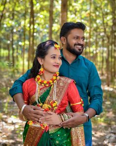 a man and woman standing next to each other in the woods