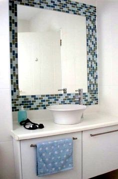 a bathroom with a sink, mirror and towel on the counter top in front of it