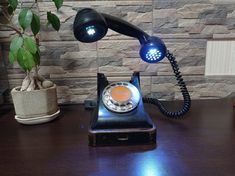 an old fashioned telephone sitting on a desk next to a potted plant