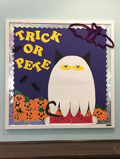 a trick or treat sign with a cat and pumpkins in the background on a blue wall