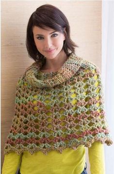 a woman standing next to a wall wearing a crocheted shawl with flowers on it