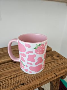 a pink and white coffee cup sitting on top of a wooden table next to a wall