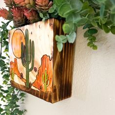 a wooden box with plants in it hanging on the wall next to a potted plant