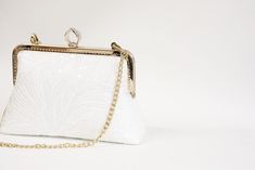 A must have accessory for elegant occasion ensembles This modern-romantic white bridal clutch purse is romance in its purest form, featuring beautiful Off-white lace with delicate sequins. The lining is beautiful silk and can be any color, secured closure with rose gold purse frame. Comes with chain or you can adding pearl handle to represent the essence of vintage romance! This clutch purse is suitable for weddings, both formal and informal party and big enough to carry all your most needed essentials.  Dimensions: Frame width : 8" (measured across the opening)  Height : 6.5" (measured across the center)  Bottom width : 9" Depth : 2" Removeable Chains : 17" Don't see what you need listed in my shop? Feel free to contact me for a special request. I love working on custom designs to match a Vintage Romance Wedding, Rose Gold Purse, Bridal Clutch Purse, Lace Clutch, Banquet Dress, Romance Wedding, Gold Purse, Purse Frame, Wedding Clutch