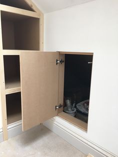 an empty room with open cupboards in the corner and shoes on the floor next to it