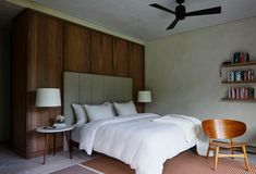 a bed sitting in a bedroom next to a wall mounted book shelf with books on it