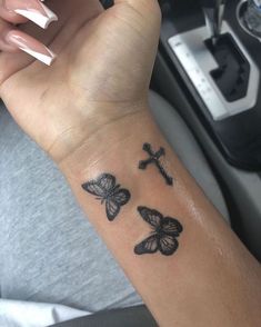 a woman's arm with three butterflies and a cross tattooed on the left wrist