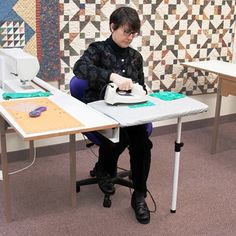 a person sitting at a table with an ironing board and sewing machine on it