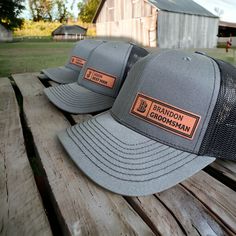 two hats sitting on top of a wooden bench in front of a barn and silo