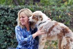 a woman sitting on a bench hugging her dog