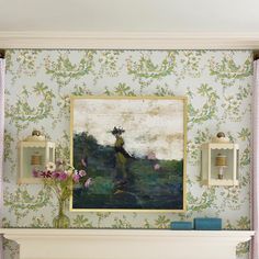 a painting hangs on the wall above a fireplace in a room with floral wallpaper